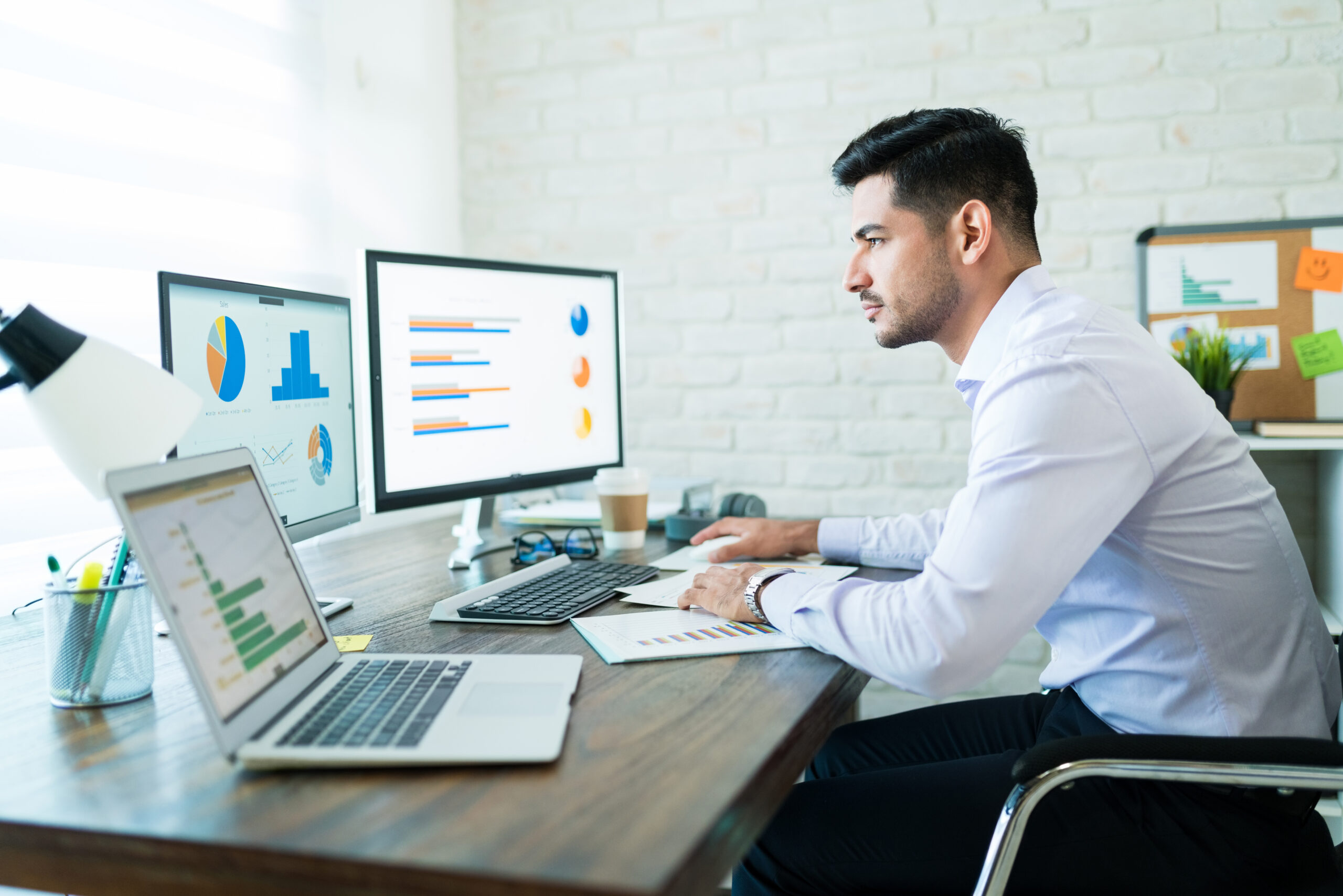 side view young attractive businessman studying charts computer while working home 1 scaled