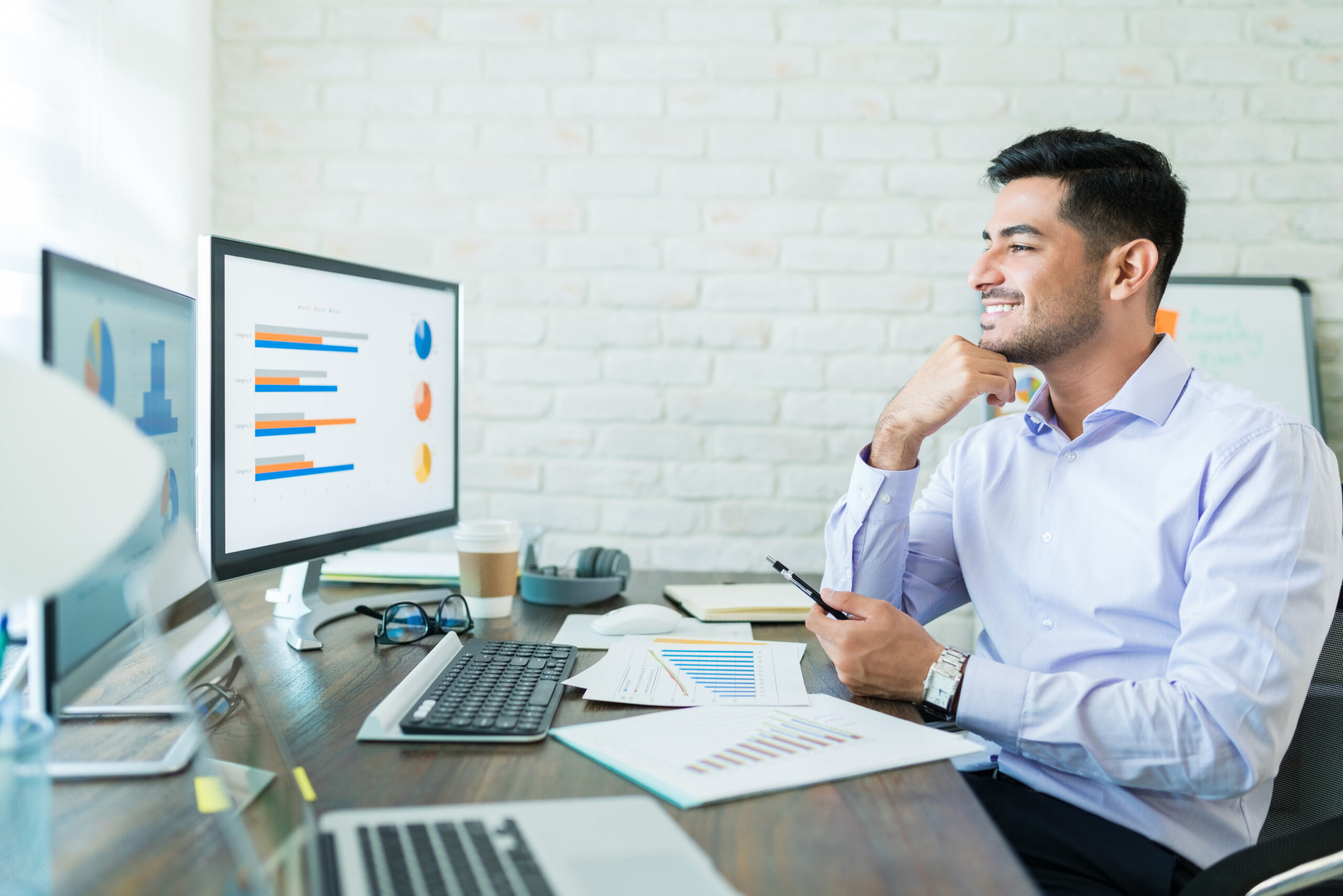 young businessman looking charts computer while sitting with smartphone scaled
